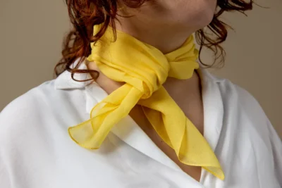 Écharpe jaune nouée autour du cou sur chemisier blanc.